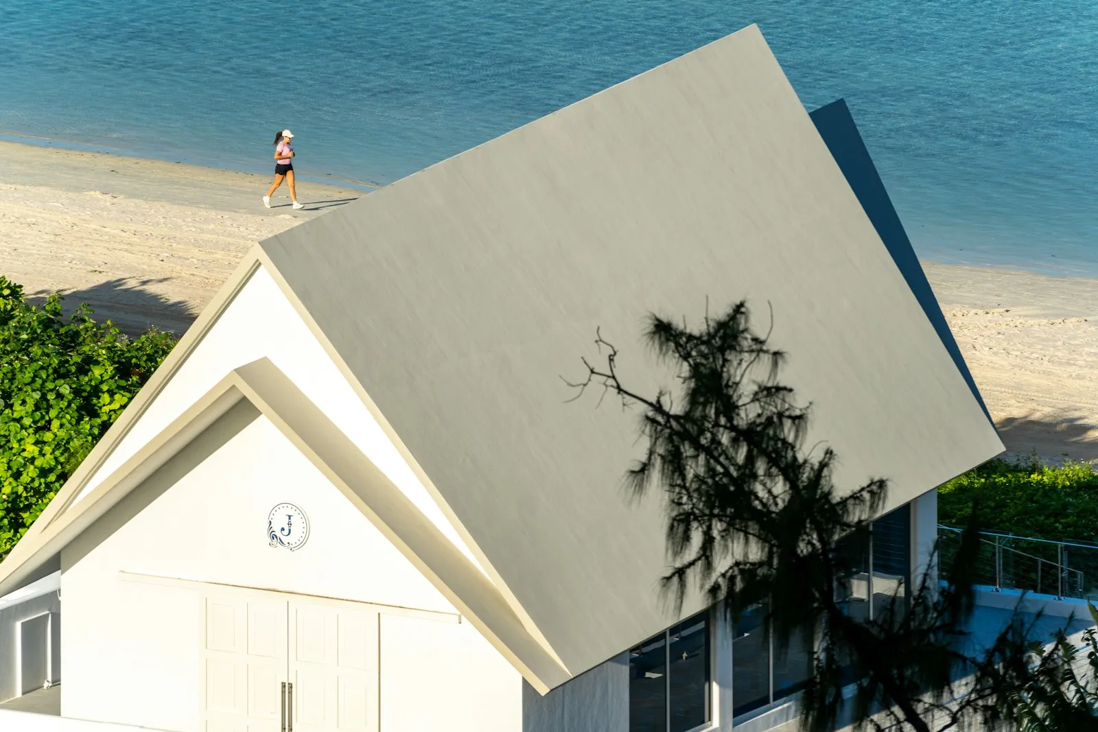 A person walking on a beach next to a house