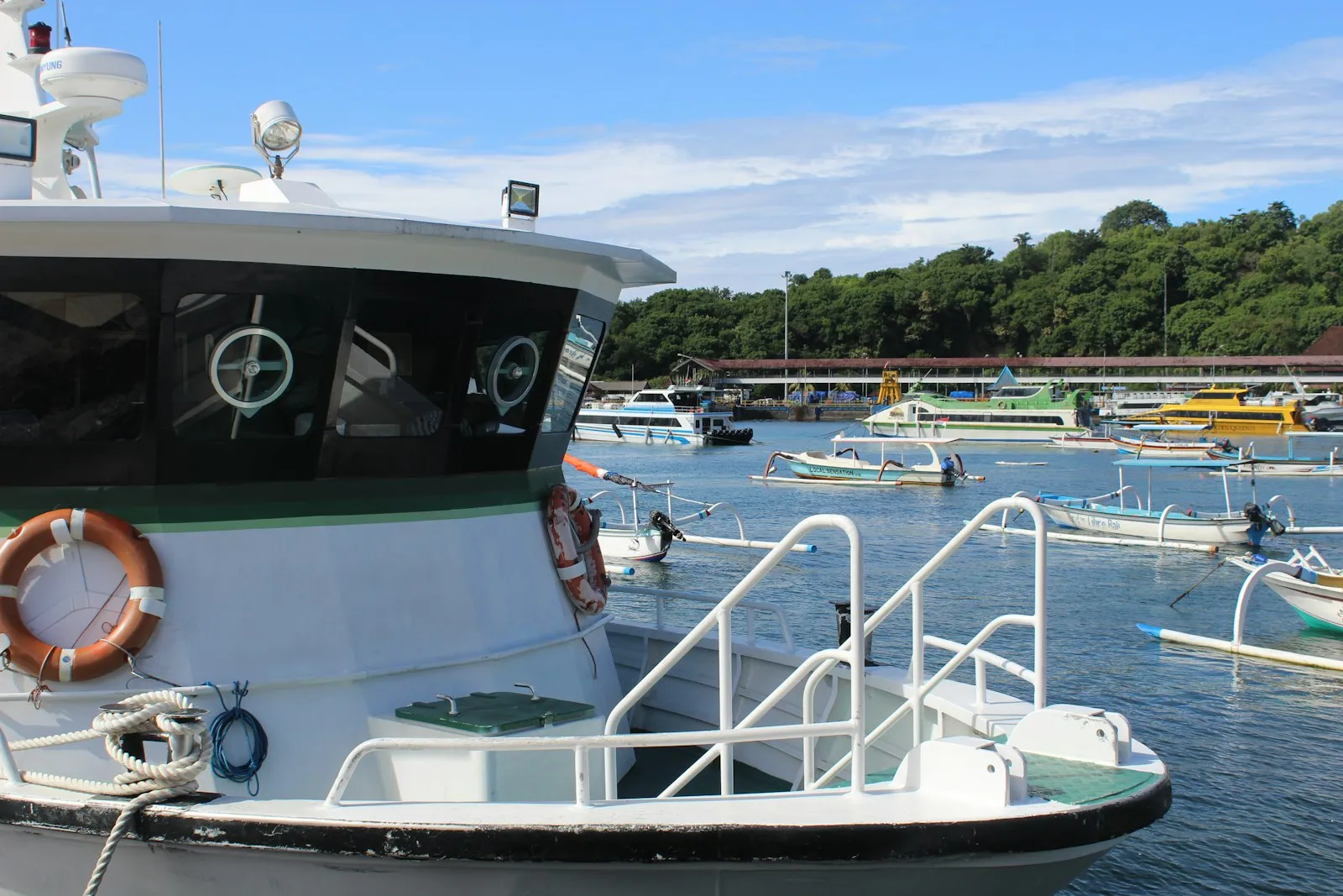 A boat docked at a dock with other boats in the water
