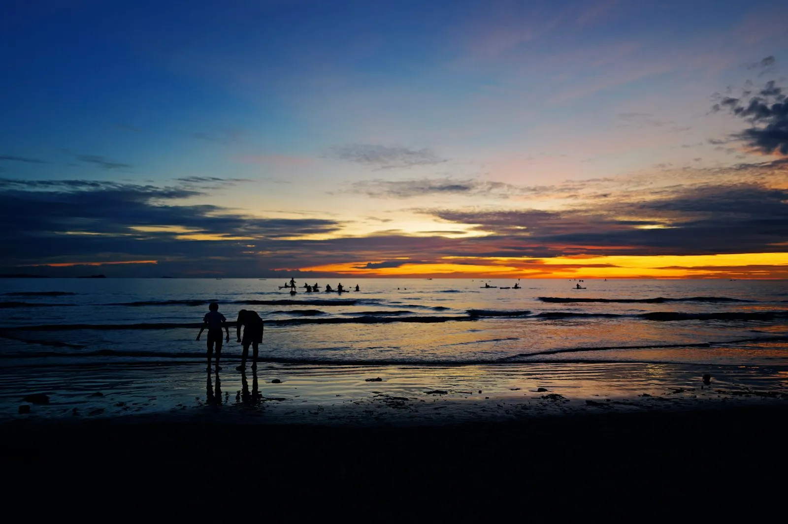 A couple of people standing on top of a beach